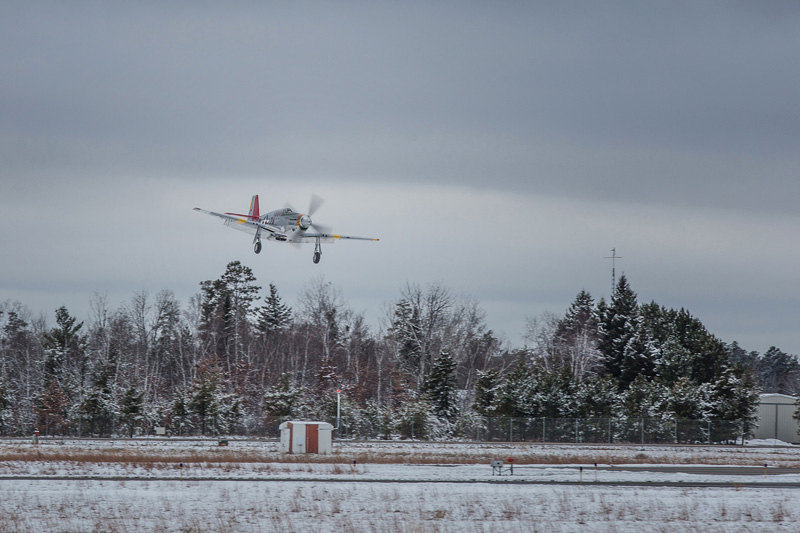 The Red Tail lands after a successful test flight with a background of snow.