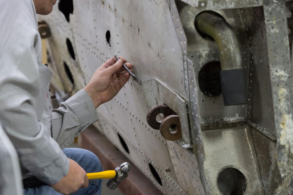 Robb drills a pilot hole into the rivet head and then chisels off the remaining part of the head. This is done so that the hole for the rivet shaft isn’t wallowed out.