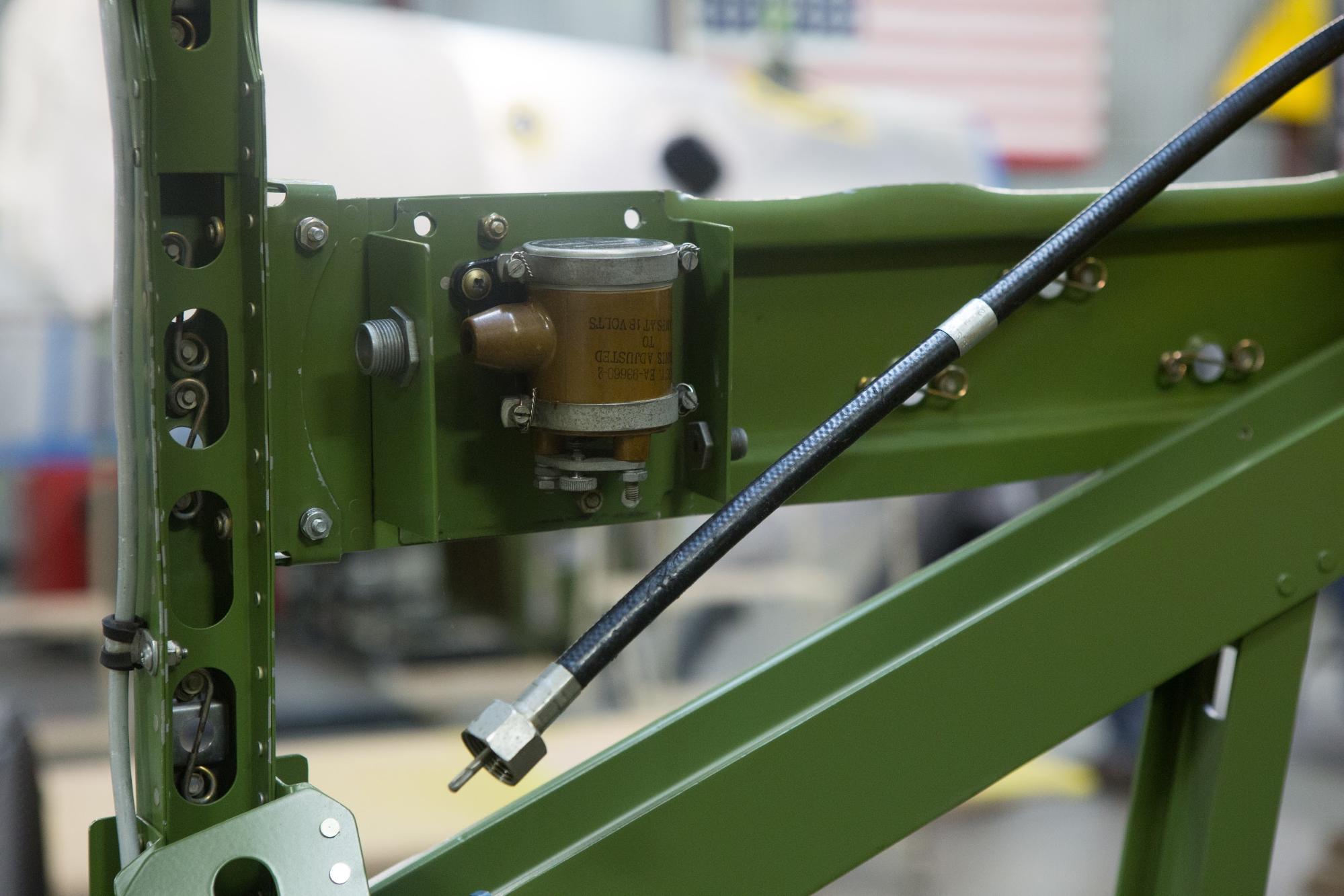 The brown colored “shower of sparks” or “buzz box” provides ignition spark to the magnetos when the engine is being started but not yet rotating fast enough for the magnetos to generate sufficient power to provide the spark on their own. The heavy black cable is the tach drive cable.