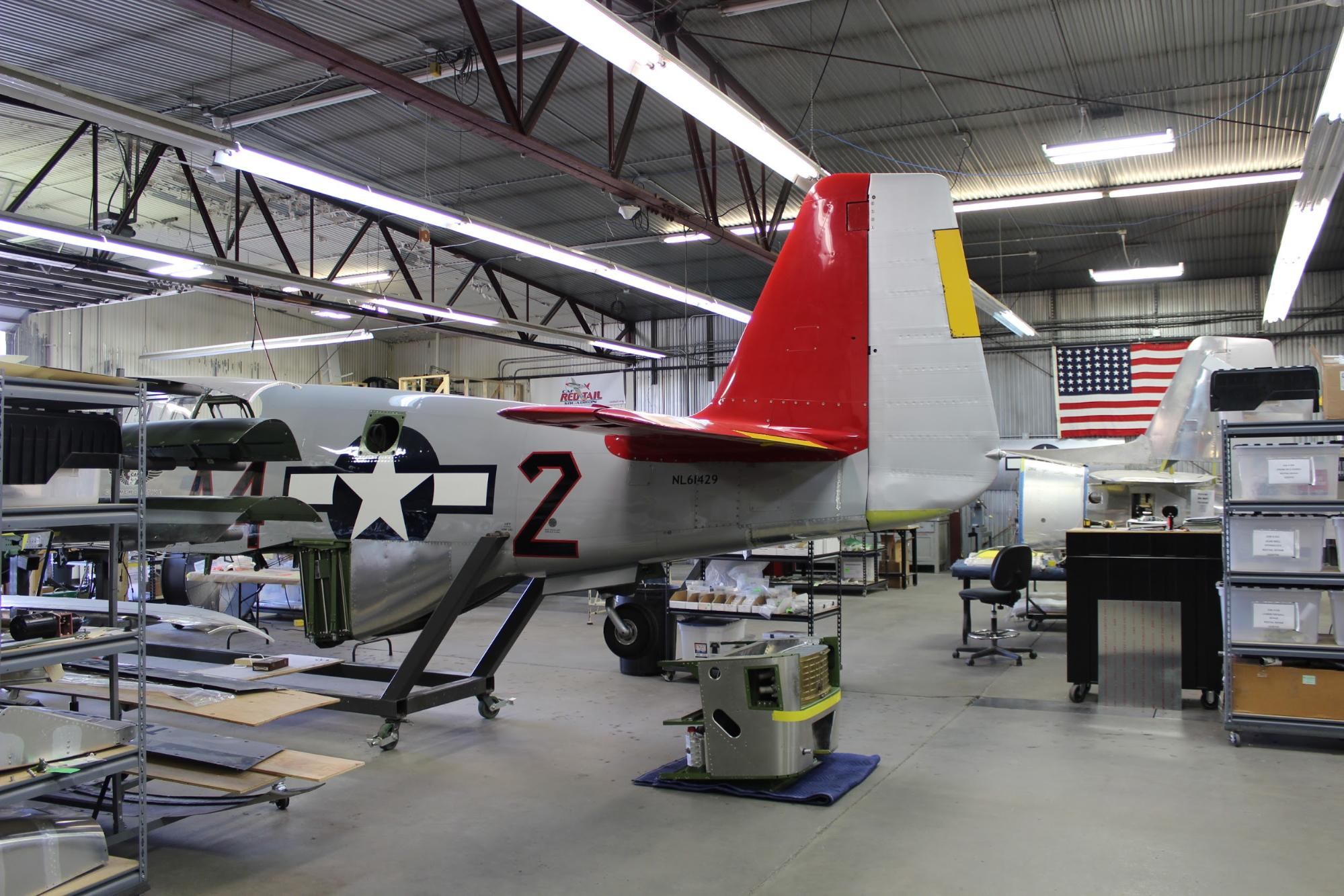 Here is an opposite side view of the red tail feathers. In this shot, the finished dog house sits on the floor under the tail. It awaits final fitting of the holes that connect it to the scoop. Once that fitting is complete, the dog house and scoop go on permanently.